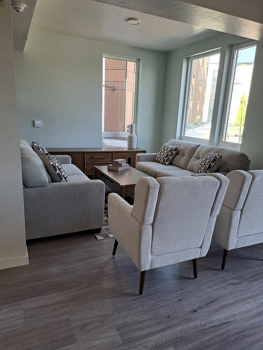 A living room with a grey couch and two chairs.